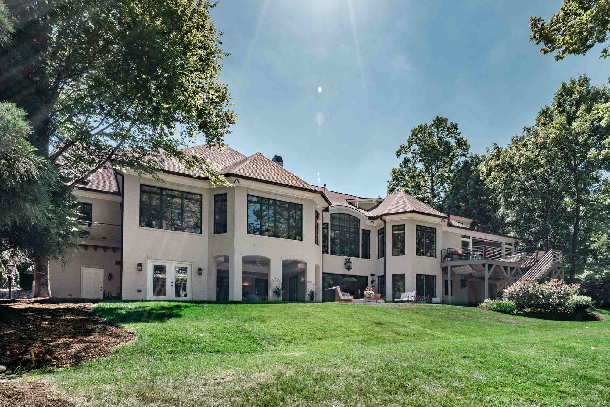 Rear view of a custom-built home by Wolfe Homes in Greensboro, NC, showcasing expansive windows and lush lawn