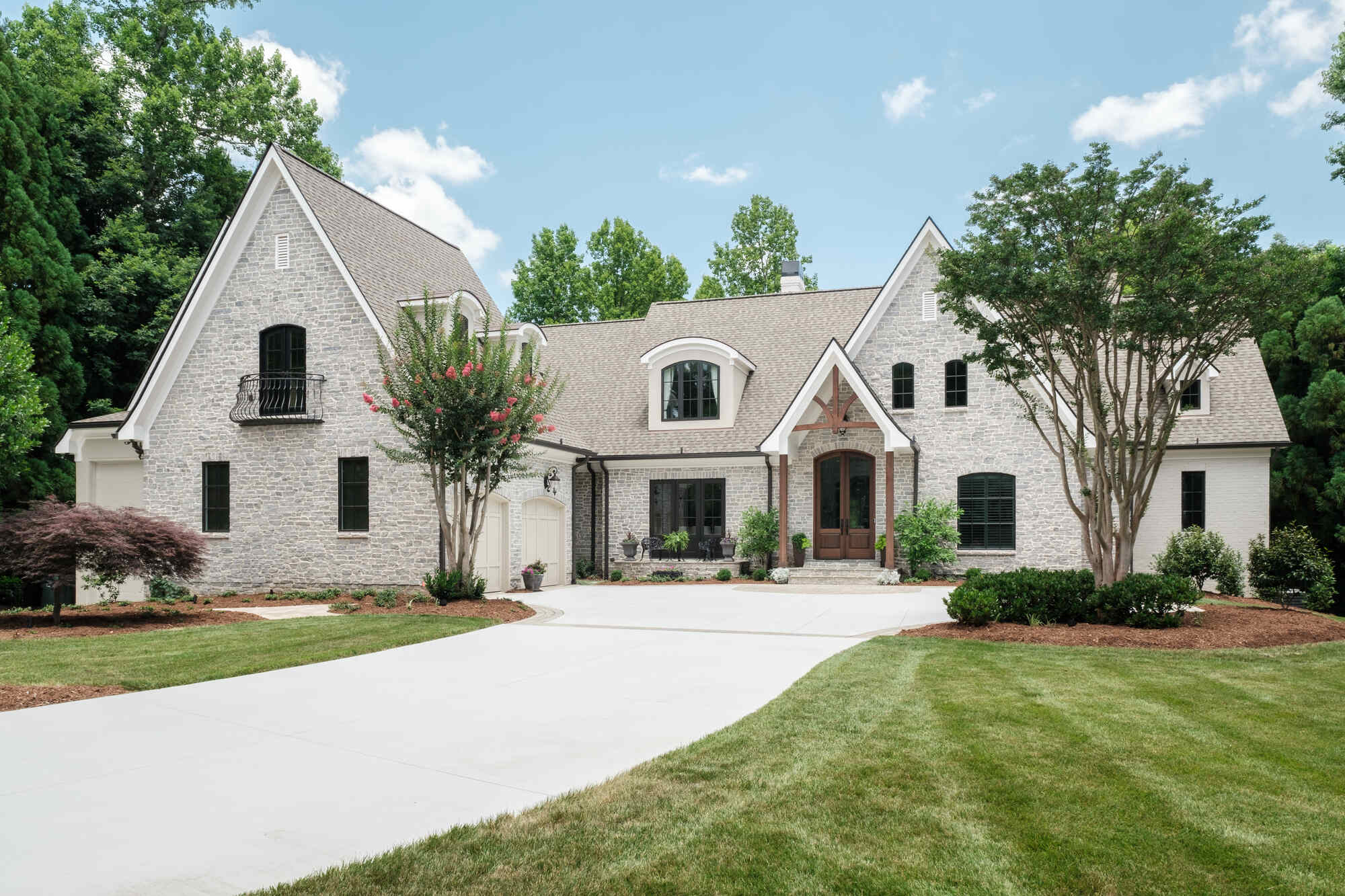 Stunning stone exterior of custom-built home by Wolfe Homes in Greensboro, NC, with well-maintained landscaping