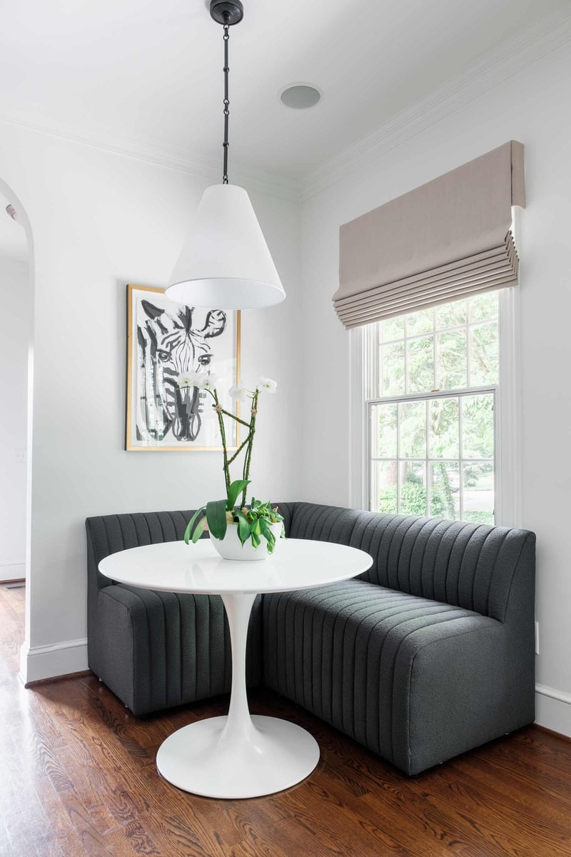 Bright breakfast nook with gray seating and white table, part of a Greensboro custom remodel by Wolfe Homes