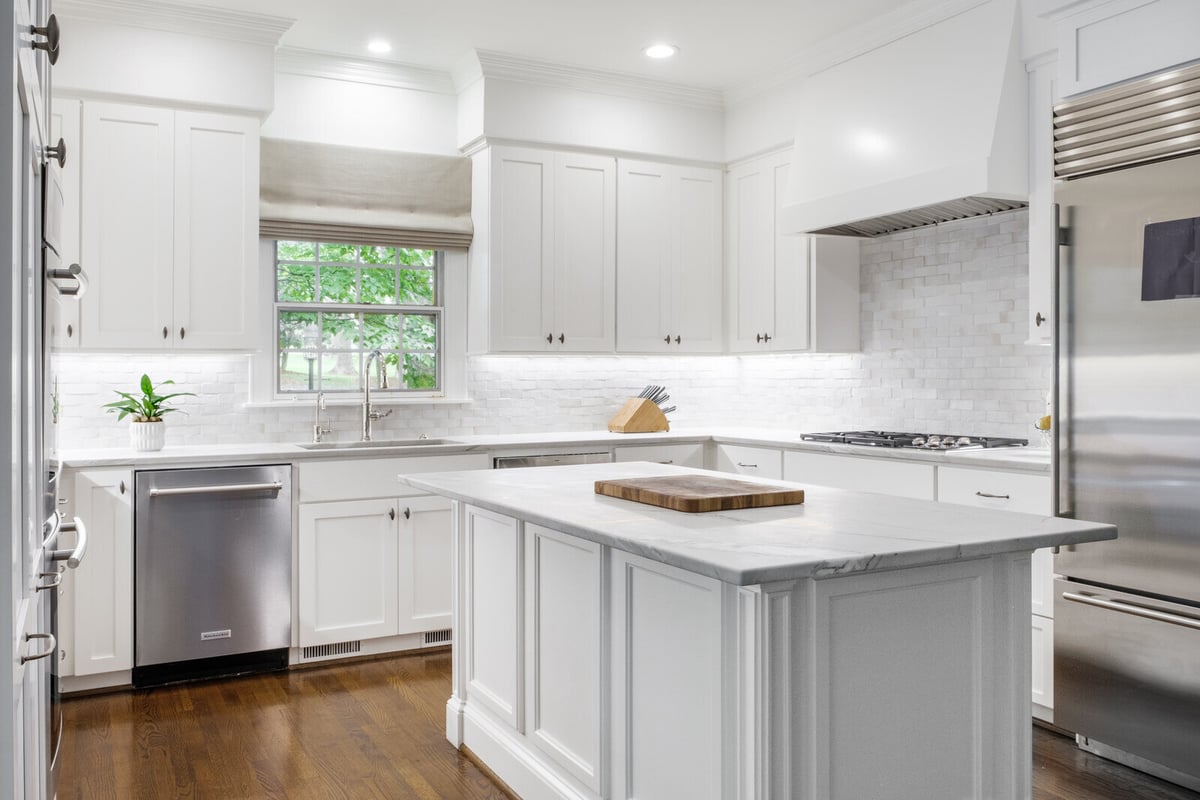 Bright, all-white kitchen with center island and stainless steel appliances in a custom Greensboro remodel by Wolfe Homes