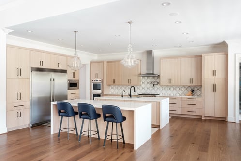 Modern kitchen with light wood cabinetry and island seating by Wolfe Homes in Greensboro, NC