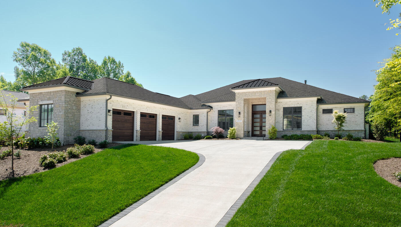 Custom stone exterior of Wolfe Homes-designed home in Greensboro, NC, with landscaped front yard and elegant entrance