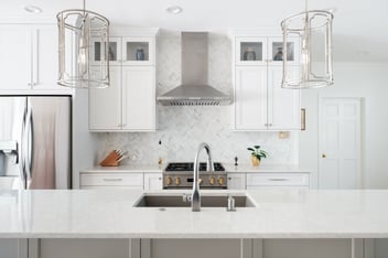 Remodeled kitchen, bright white tiles, cabinetry and custom countertop. Sterling silver hardware, hood and pendant lamps