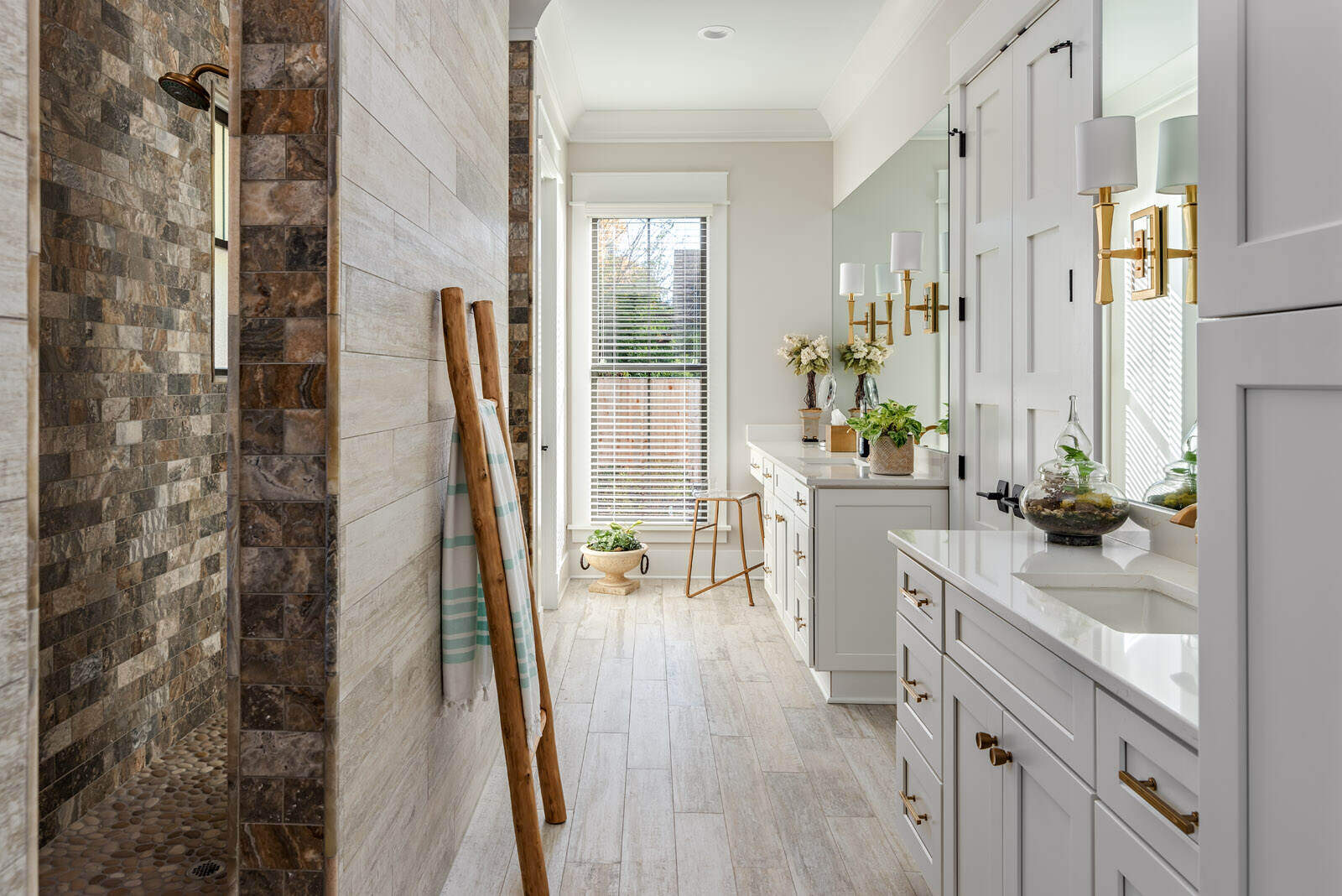 Luxurious master bathroom remodel in Greensboro by Wolfe Homes with dual vanities and stone accent shower