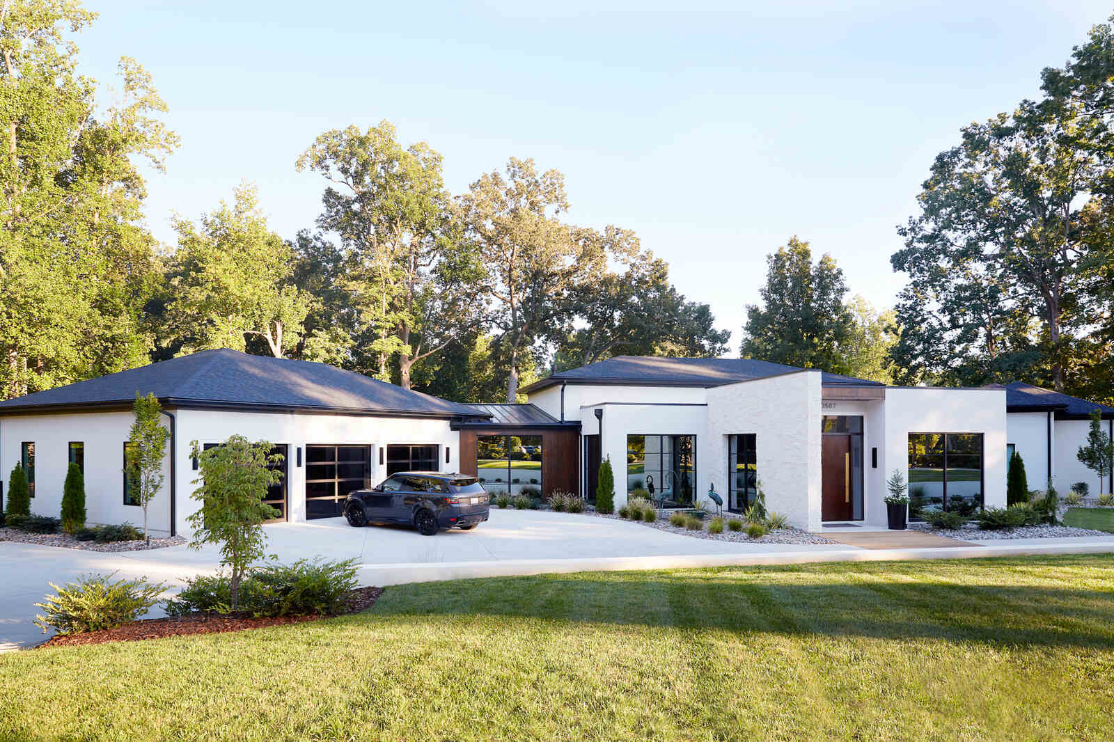 Modern white exterior of a custom-designed home with lush landscaping by Allen & James in Gaston County