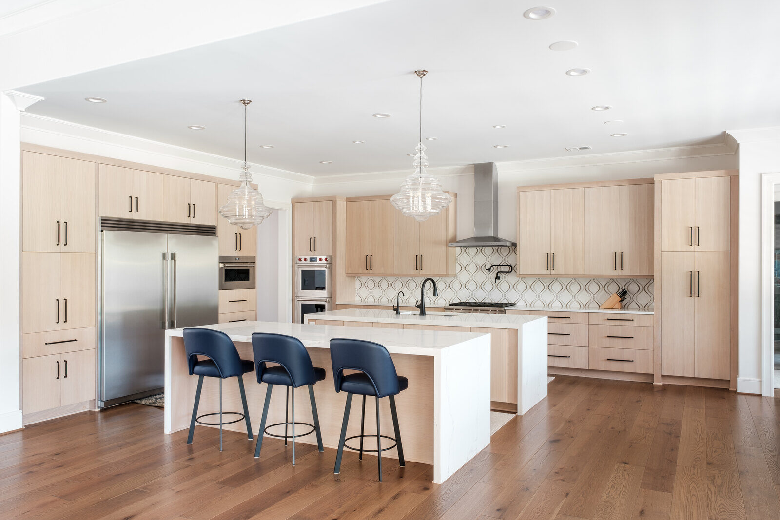 Modern kitchen with light wood cabinetry and island seating by Wolfe Homes in Greensboro, NC