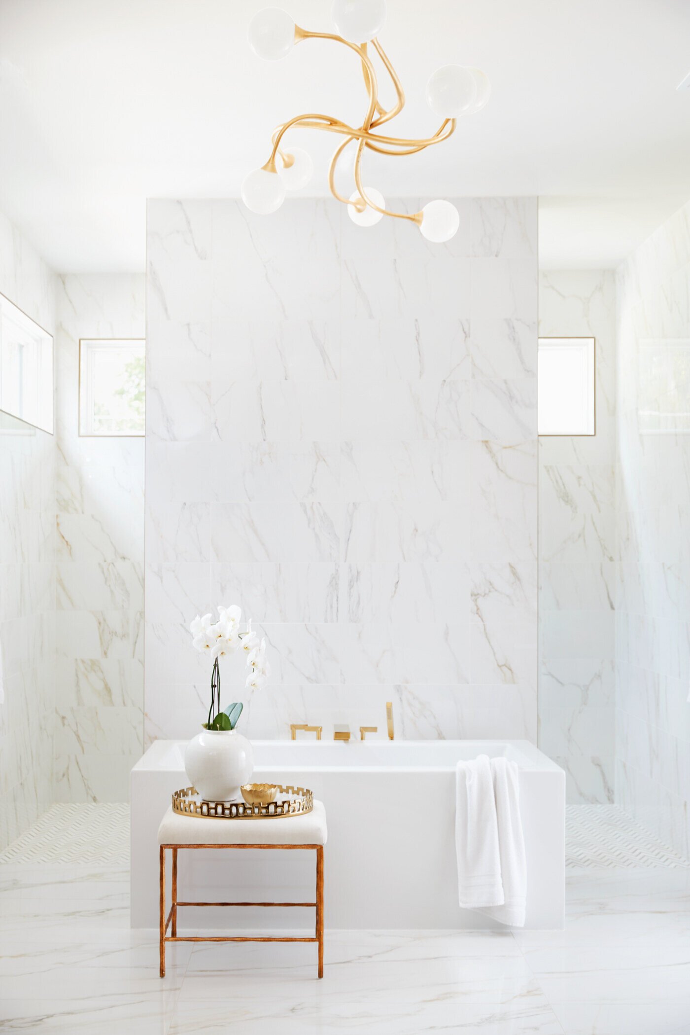 Luxurious marble master bathroom in Greensboro custom home by Wolfe Homes, featuring a freestanding tub and gold accents