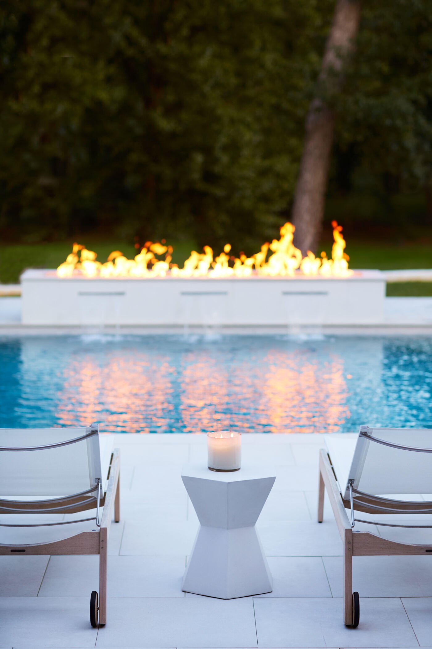 Luxurious poolside fire feature in Greensboro custom home by Wolfe Homes, creating a serene outdoor atmosphere