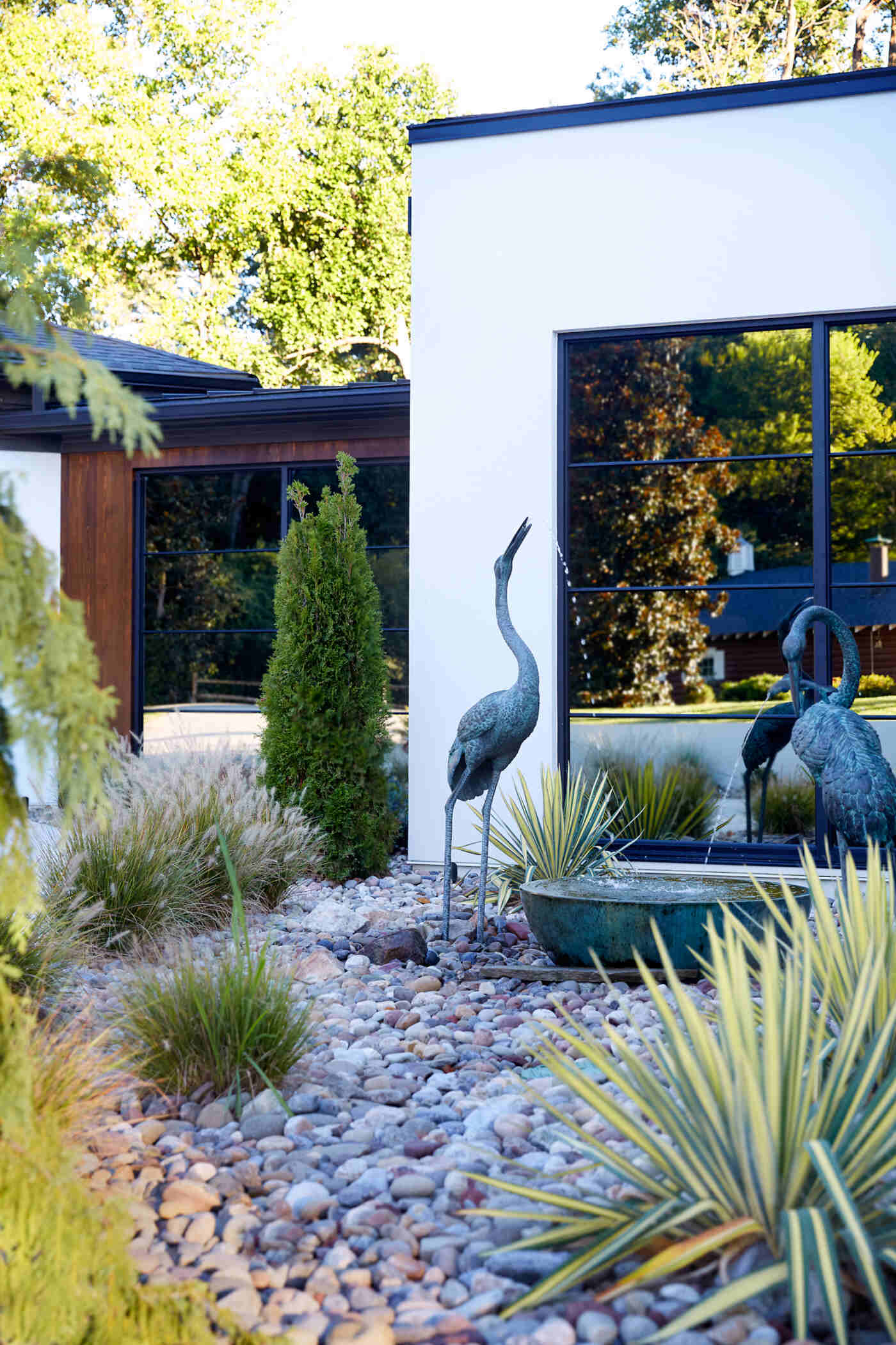 Sleek modern entry of Greensboro custom home by Wolfe Homes, featuring minimalist landscaping and glass accents