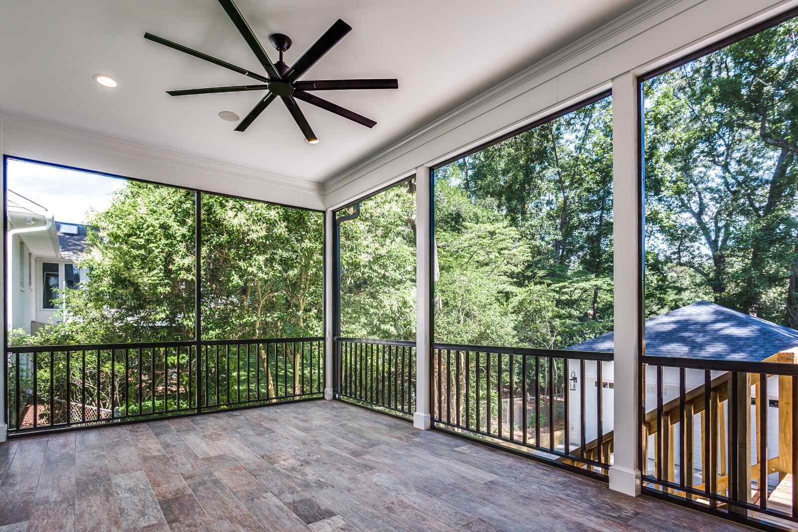 Screened porch with sleek black railing and wooded backyard views by Wolfe Homes in Greensboro, NC