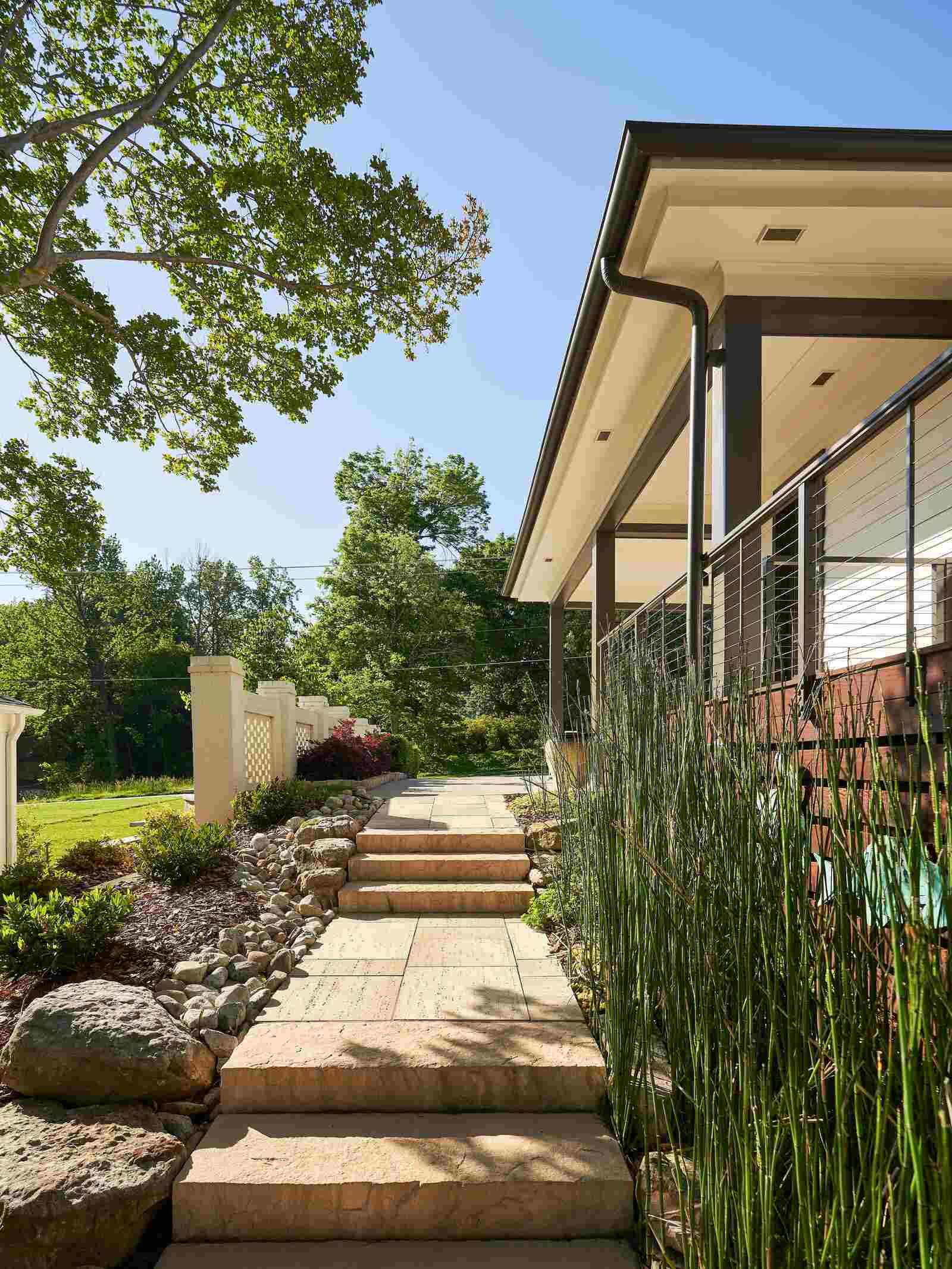 Stone walkway surrounded by lush landscaping leading to a modern porch in Greensboro, NC by Wolfe Homes