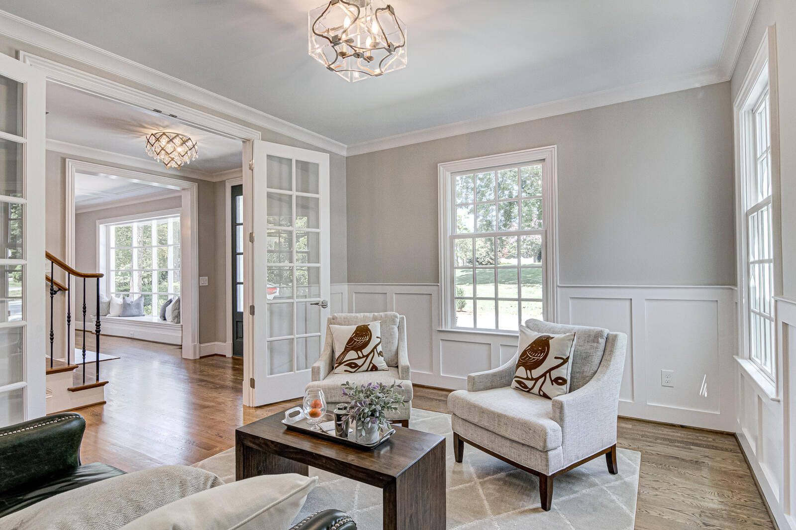 Bright and airy living room with French doors and elegant wainscoting by Wolfe Homes in Greensboro, NC