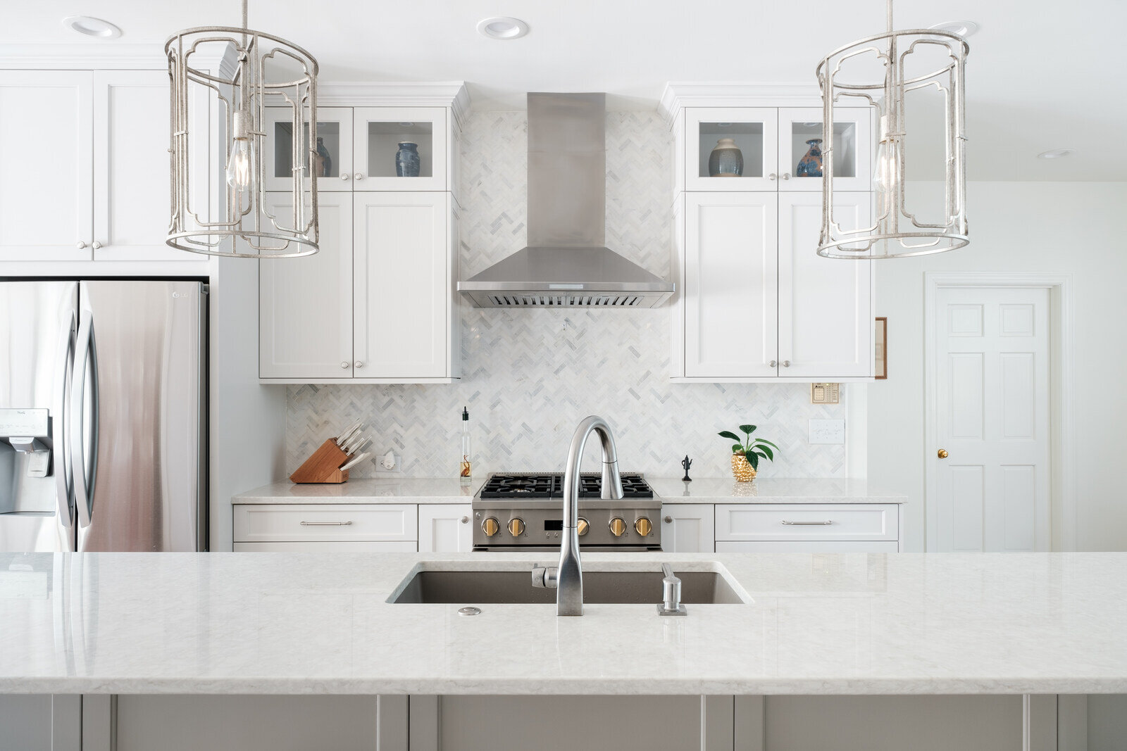 Bright white kitchen with marble countertops and stainless steel appliances by Wolfe Homes in Greensboro, NC